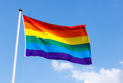 Rainbow flag proudly waving against the blue sunny skies